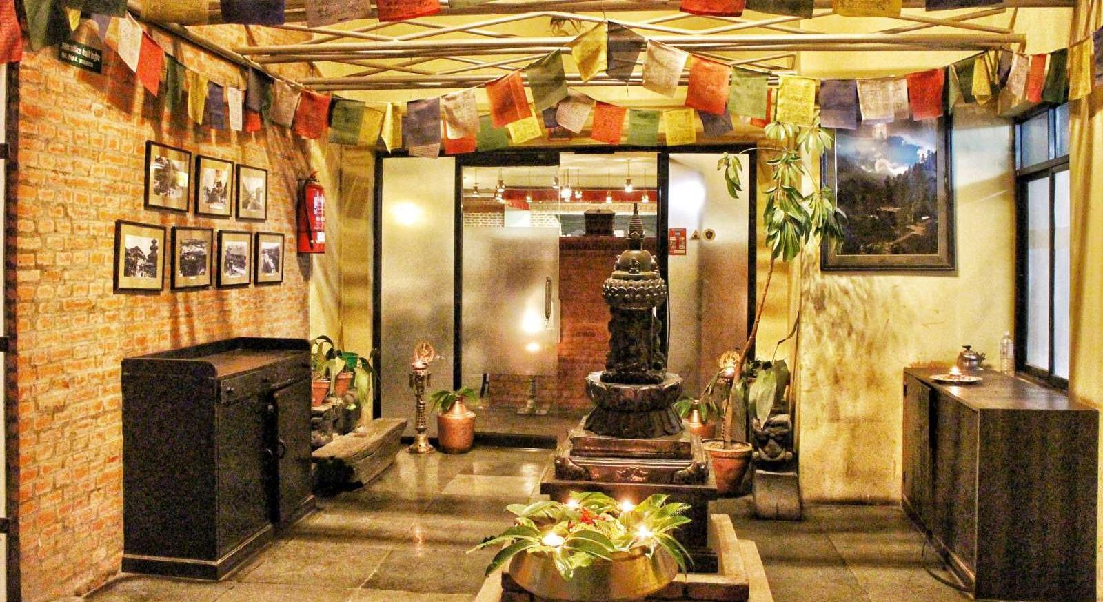 Brass shrine, butter lamps and prayer flags in Utsav's entrance courtyard, Kathmandu